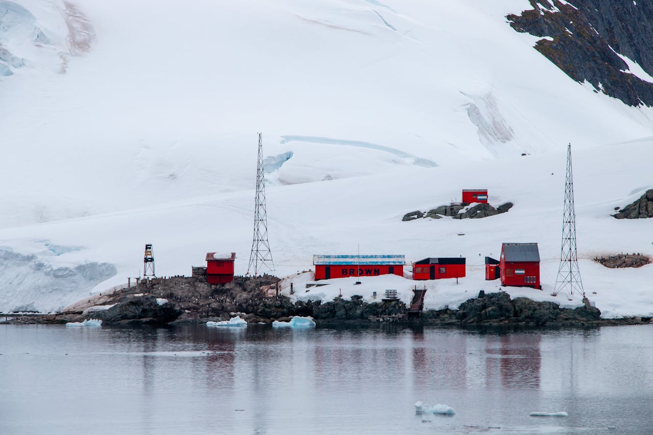 our-story Red research station nestled in Antarctica's icy landscape by the sea, showcasing remote exploration.